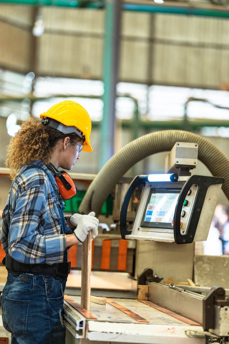 Operaria de una fábrica trabajando en una máquina CNC con panel de control digital