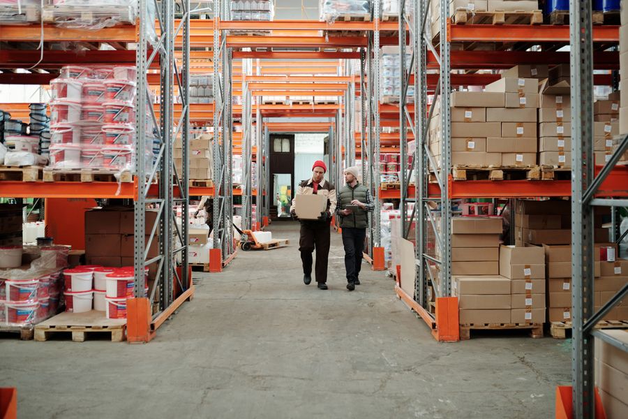 Operarios recorriendo un pasillo de almacén logístico